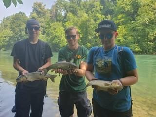 Zwei Jungfischer und ein Leiter, die je einen Fisch gefangen haben